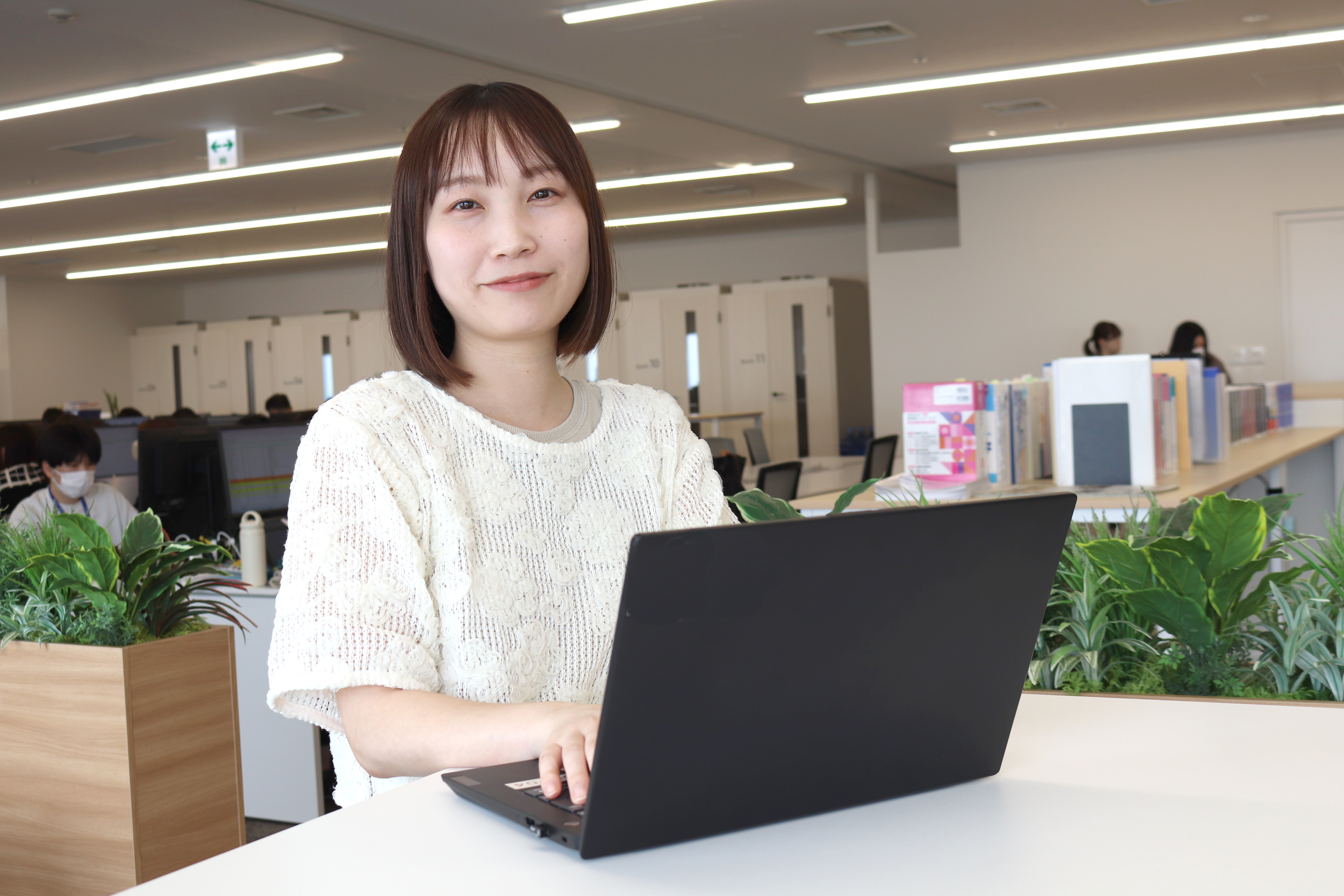 オフィスでノートPCを操作する笑顔の女性